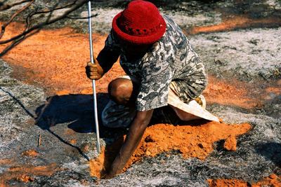 Woman Digging a Lizard from Its Hole