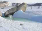 A rock thrown by Sujoy lands in a melt-pond beneath a large granite boulder.